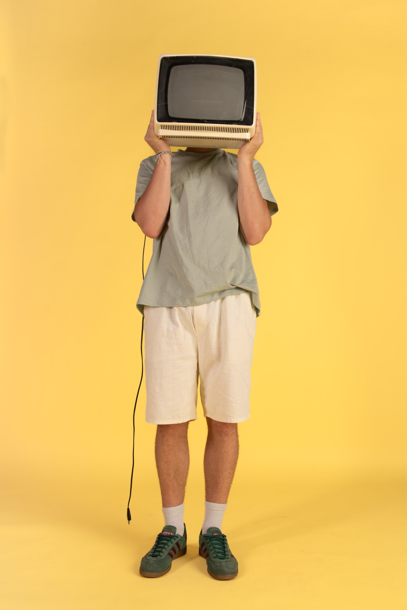 Konceptualni studijski portret s televizorjem na rumenem ozadju